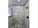 Stylish shower featuring marble-patterned tile walls and a geometric tile floor at 1064 Eastview Ne Rd, Conyers, GA 30012