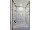 Stylish shower and tub featuring marble-patterned tile walls and black hardware at 1064 Eastview Ne Rd, Conyers, GA 30012