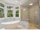 Bathroom featuring a luxurious soaking tub, a glass enclosed shower, and bright windows at 725 Riley Pl, Sandy Springs, GA 30327