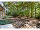 Landscaped backyard with stone accents, a multi-level deck, mature trees, and lush greenery at 1585 Lazy River Ln, Sandy Springs, GA 30350