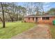 A cozy brick home featuring a spacious front lawn and mature trees at 1678 Capistrana Pl, Decatur, GA 30032