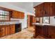 An older kitchen features wood cabinets and a breakfast bar open to an adjacent room at 1678 Capistrana Pl, Decatur, GA 30032