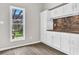 Kitchenette featuring white cabinets, natural stone backsplash, laminate flooring, and a window view at 1765 Round Rd, Grayson, GA 30017