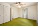 Standard bedroom featuring a ceiling fan, closet, and worn green carpet at 1007 E Callaway Sw Rd, Marietta, GA 30060