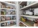 Well-organized walk-in pantry with wooden shelves and wire baskets filled with groceries and kitchen supplies at 1331 Dayspring Trce, Lawrenceville, GA 30045