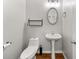 Efficient bathroom with a toilet, pedestal sink, decorative mirror, and a wooden shelf; the walls are painted a neutral gray at 1152 Liberty Nw Pkwy, Atlanta, GA 30318