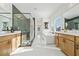 Bright bathroom with dual vanities, soaking tub, and frameless glass shower with tiled walls and floor at 2018 Stonecreek Dr, Woodstock, GA 30188
