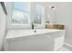 A modern white soaking tub is in a bright bathroom with wooden cabinets and large window views at 2018 Stonecreek Dr, Woodstock, GA 30188