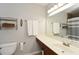Bright bathroom with a long white countertop, brown cabinets, and large mirror at 125 N River Dr # F, Atlanta, GA 30350