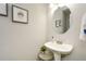 Small bathroom with a pedestal sink, large round mirror, and modern fixtures at 125 N River Dr # F, Atlanta, GA 30350