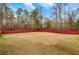 Spacious backyard is enclosed by a vibrant red privacy fence, offering an ideal space for outdoor activities at 10 Oakbrook Ln, Covington, GA 30016