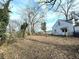Backyard showing a detached house, trees, and overgrown yard with sparse grass at 1413 Lanier Ne Pl, Atlanta, GA 30306