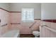 Bathroom featuring pink wall tile, a white toilet, a bathtub, and accessibility grab bars at 1850 Brewer Sw Blvd, Atlanta, GA 30310