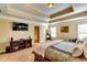 Relaxing main bedroom featuring a tray ceiling, plush carpet, and a stately bed with a mounted TV at 3135 Preservation Cir, Lilburn, GA 30047