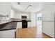 Kitchen featuring wood floors, white cabinetry, black appliances, and a window view at 6474 E Meyer Dr, Morrow, GA 30260