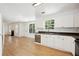 Open kitchen with white cabinets, stainless dishwasher, and hardwood floors flowing into living area at 6474 E Meyer Dr, Morrow, GA 30260