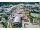 Aerial view featuring mixed-use community with apartments, a shopping center, an amphitheater, and a scenic pond at 608 Sweetfern Ln, Sugar Hill, GA 30518