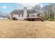 Spacious backyard with a home featuring a deck and staircase, and treeline in the distance at 1070 Thornwood Cir, Covington, GA 30016