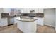 Well-lit kitchen featuring white cabinets, an island, stainless steel appliances, granite countertops, and mosaic backsplash at 10950 Glenhurst Pass, Duluth, GA 30097