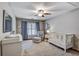 Bright Bedroom features a white crib, changing table, chair and ottoman, ceiling fan and blue curtains at 4580 Windsor Park Place, Atlanta, GA 30342