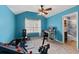 Bedroom with blue walls, ceiling fan, and exercise equipment next to an ensuite bathroom at 923 Buckhorn Bnd, Locust Grove, GA 30248