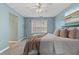 Cozy bedroom featuring blue walls, ceiling fan, natural light, and plush decorative pillows at 923 Buckhorn Bnd, Locust Grove, GA 30248