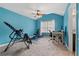 Bedroom with blue walls, ceiling fan, and exercise equipment next to an office area at 923 Buckhorn Bnd, Locust Grove, GA 30248