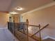 Carpeted second-floor hallway with wooden and iron railing and neutral color scheme at 1831 Nours Landing Way, Duluth, GA 30097