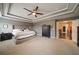 Large main bedroom boasts tray ceilings, modern fan, neutral carpeting, and elegant dark wood furnishings at 322 Kells Ct, Woodstock, GA 30188