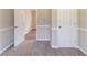 A carpeted bedroom with two white doors, neutral walls, and a view into another room at 4124 Casa Loma Dr, Decatur, GA 30034