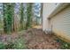 View of the side of the home, concrete patio, and wooded backyard filled with mature trees at 821 Stonebridge Park Cir, Lithonia, GA 30058