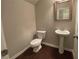 A small half-bath with a toilet, pedestal sink, and framed mirror at 5223 Catrina Way, Buford, GA 30519
