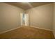 A simple bedroom with neutral walls, beige carpet, and a view into the hallway at 5223 Catrina Way, Buford, GA 30519