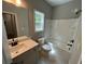 Bright bathroom with a combination tub and shower, gray vanity, and window at 117 Legends Way, Hiram, GA 30141