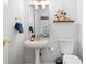 Bathroom with pedestal sink, gold hardware, toilet, and decorative floral art at 2832 Old Villa Rica Rd, Powder Springs, GA 30127
