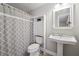 Basement bathroom features shower with gray curtain, pedestal sink, and tiled floors at 7295 Hickory Bluff Dr, Cumming, GA 30040