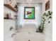 Bright bathroom featuring white bathtub with artistic stained glass window, and floating shelves at 7295 Hickory Bluff Dr, Cumming, GA 30040