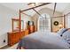 Bright bedroom featuring a wood canopy bed, large window, and classic wood dresser at 7295 Hickory Bluff Dr, Cumming, GA 30040