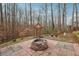 Backyard stone fire pit area with landscaping and a natural wooded backdrop at 7295 Hickory Bluff Dr, Cumming, GA 30040