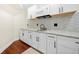 A stylish wet bar features white cabinets, granite countertops, mosaic backsplash and dark hardware at 4085 Creekview Ridge Dr, Buford, GA 30518