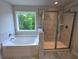 Bright bathroom featuring soaking tub and glass shower with neutral marble-style tile at 508 Clayborne Way, Loganville, GA 30052
