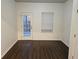 Light-filled room featuring dark laminate floors, white walls, door, and window at 6608 Saint Jude Dr, Fairburn, GA 30213