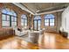 Bright open concept living room featuring exposed brick, large arched windows, and hardwood floors at 3235 Roswell Ne Rd # 917, Atlanta, GA 30305