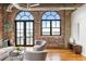 Bright living room featuring exposed brick walls, hardwood floors, and large windows at 3235 Roswell Ne Rd # 917, Atlanta, GA 30305