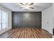 This bedroom has hardwood floors, an accent wall, and a window with neutral blinds at 128 Warm Springs Cir, Roswell, GA 30075