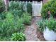 Landscaped front yard with stone path, lush plants, and a charming white picket fence and gate at 566 Wagon Wheel Climb, Lawrenceville, GA 30044