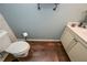 Compact half-bathroom featuring a toilet, hardwood floors, and a white vanity with decor at 58 Ashbury Cir, Dallas, GA 30157