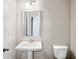 Neutral powder room featuring pedestal sink, modern mirror, and toilet at 5995 Spring Way, Stonecrest, GA 30038