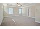 Large primary bedroom with a tray ceiling, neutral carpet and paint, with view into the ensuite bathroom at 5995 Spring Way, Stonecrest, GA 30038