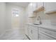 View of the laundry room with white cabinets, tile flooring and stainless steel sink at 602 Sandhill Hickory Level Rd, Carrollton, GA 30116